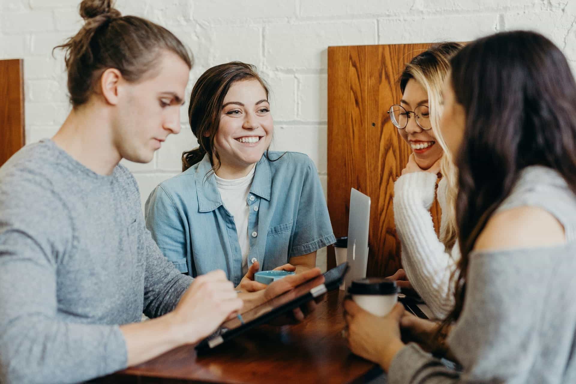 Cuatro jóvenes trabajan juntos alrededor de una mesa